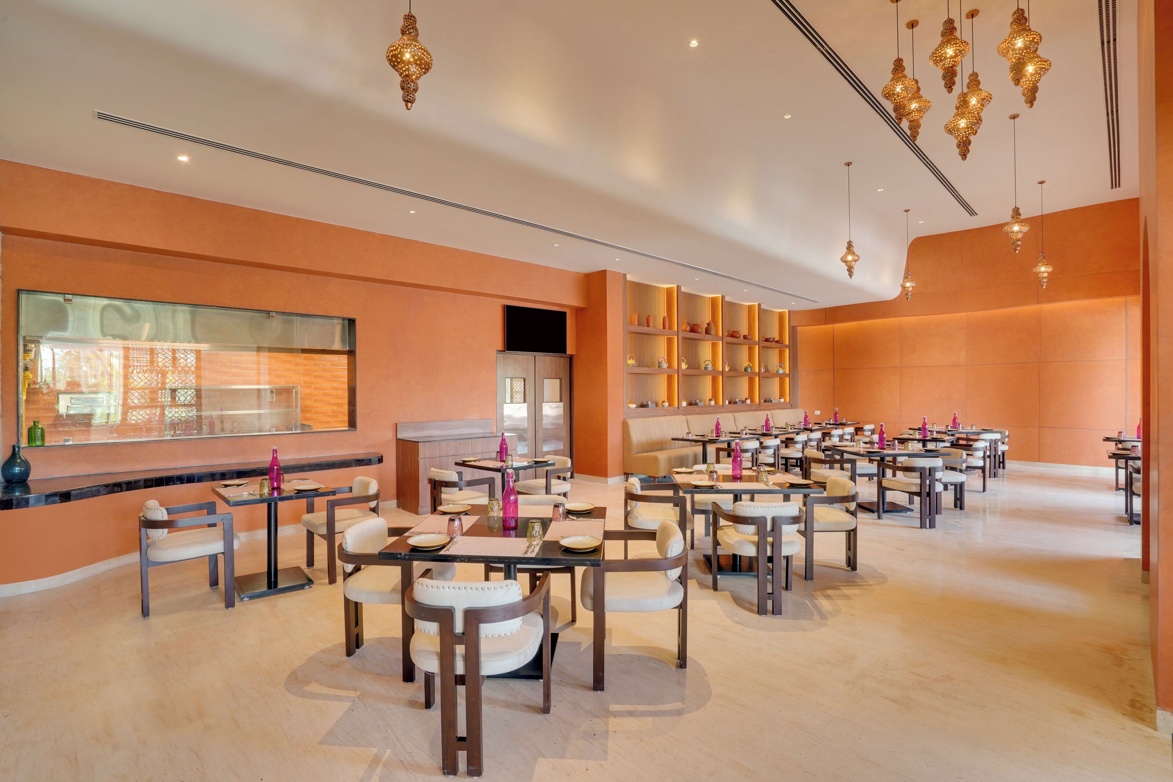 A spacious restaurant with multiple tables and chairs, a large window overlooking the street, and decorative hanging lights.