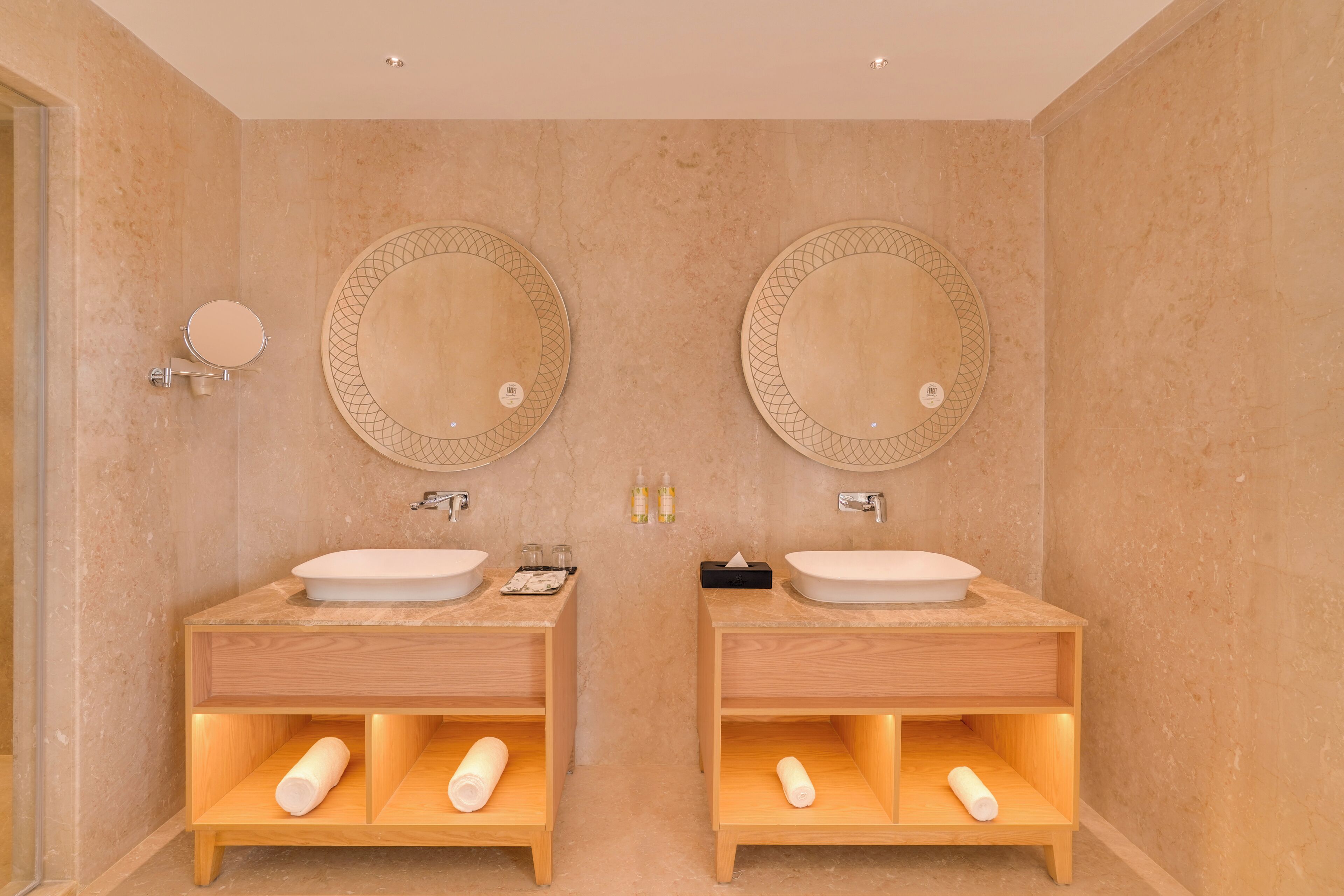 A bathroom with two sinks, each with a round mirror and a towel holder below.