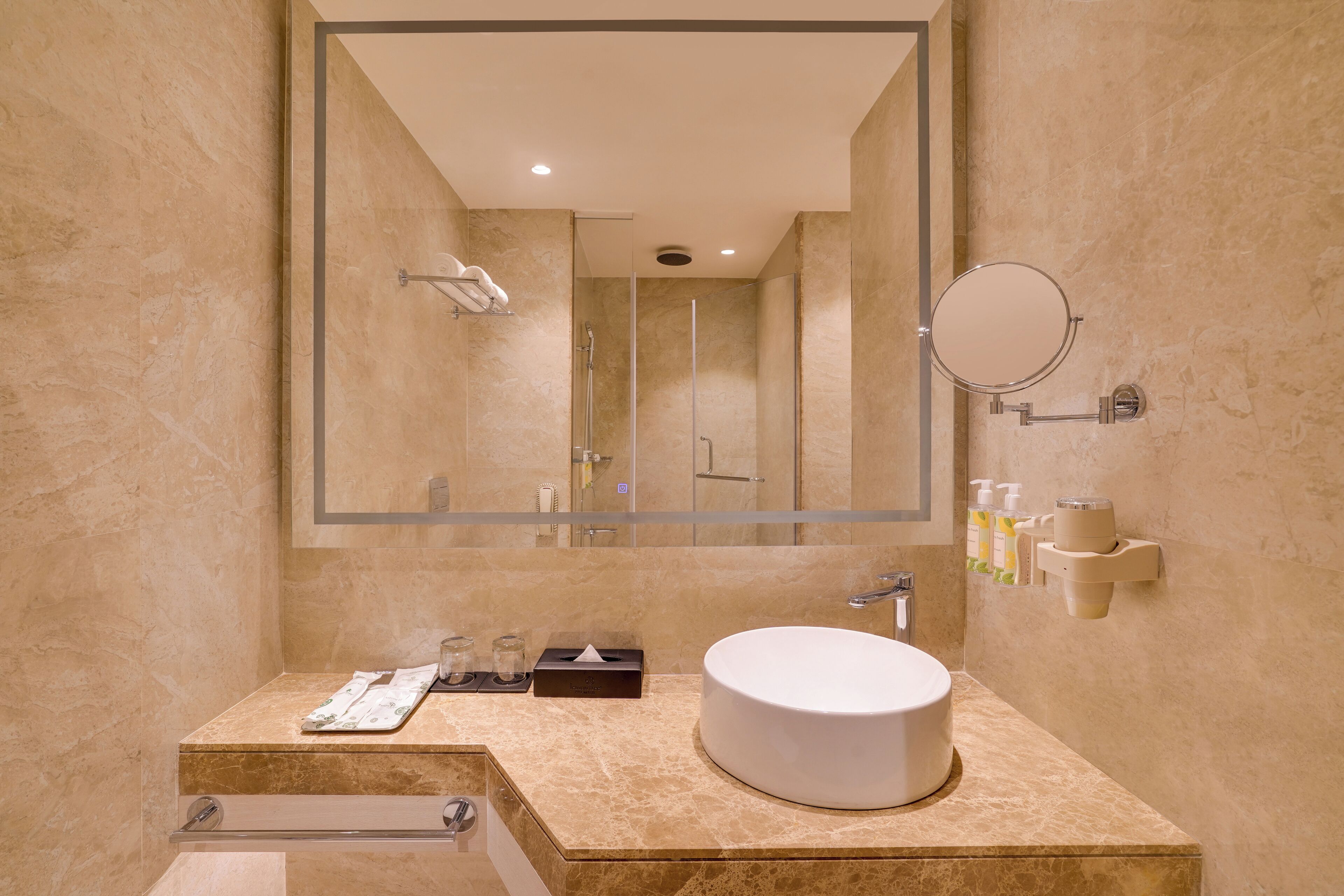 A modern bathroom with a large mirror, a round sink, and a shower area.