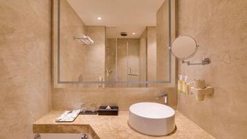 A modern bathroom with a large mirror, a round sink, and a shower area.