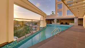 A rooftop swimming pool with clear blue water, surrounded by a modern building with large windows and a balcony. - Lemon Tree Premier Thiruvananthapuram (Thiruvananthapuram)