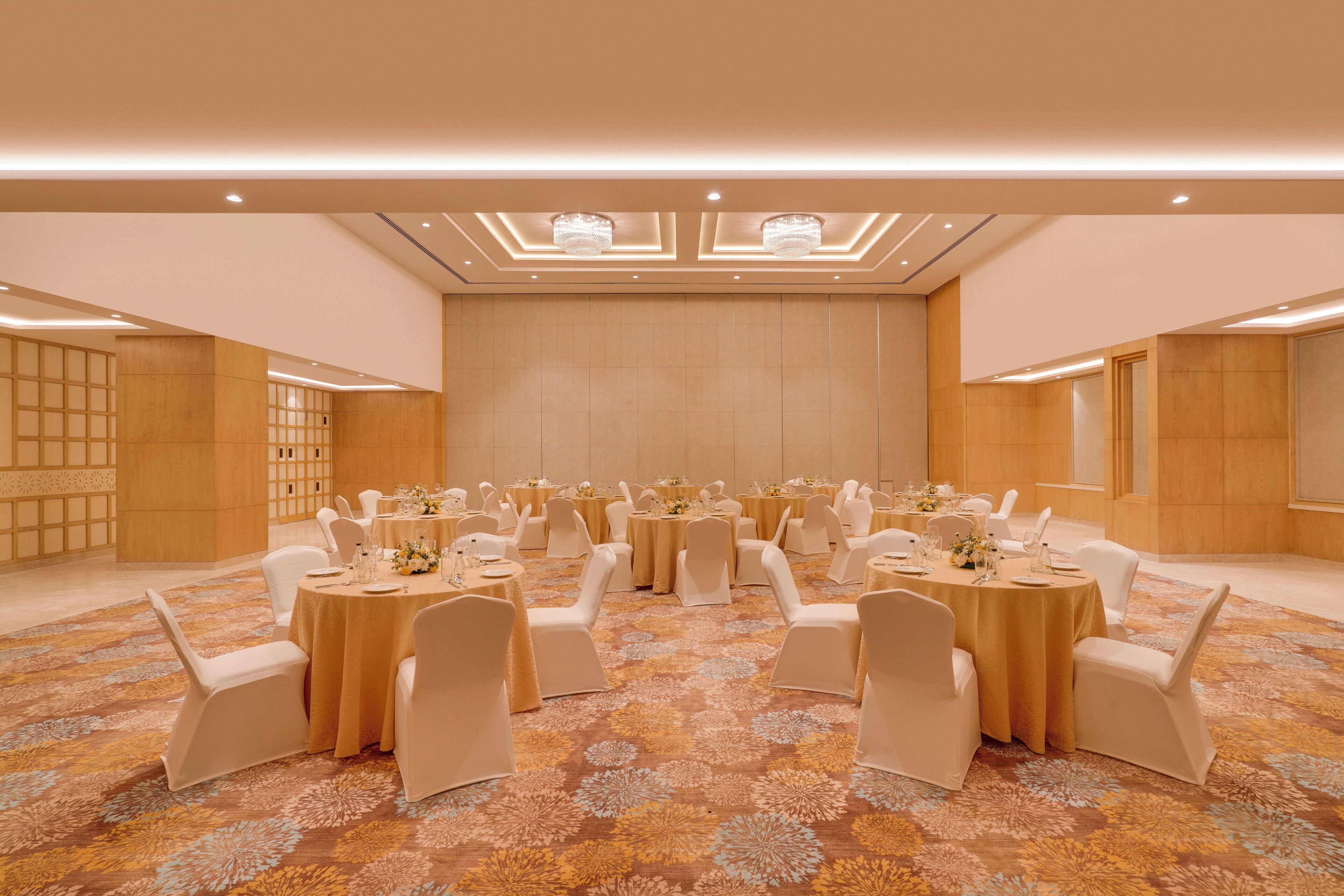 A large conference room with round tables and white chairs, arranged in rows.