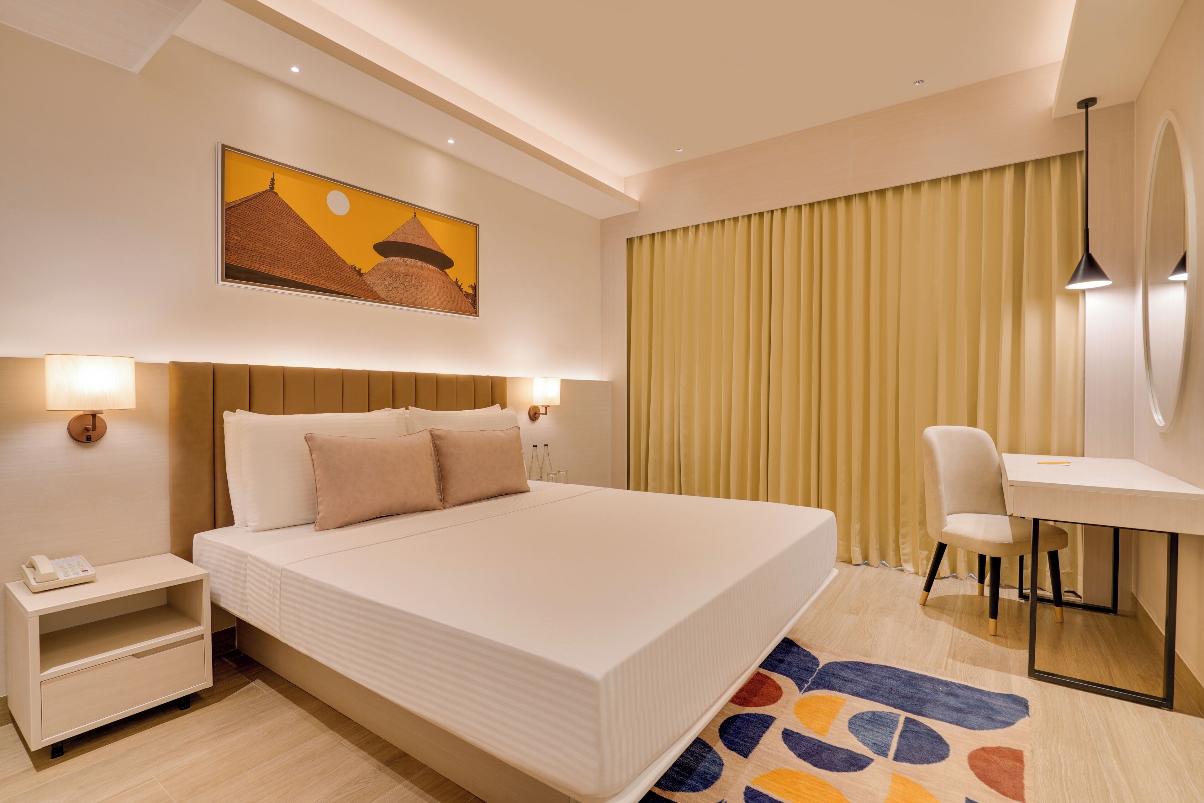 Une chambre d’hôtel avec un grand lit, des tables de chevet avec des lampes, un bureau et une chaise.