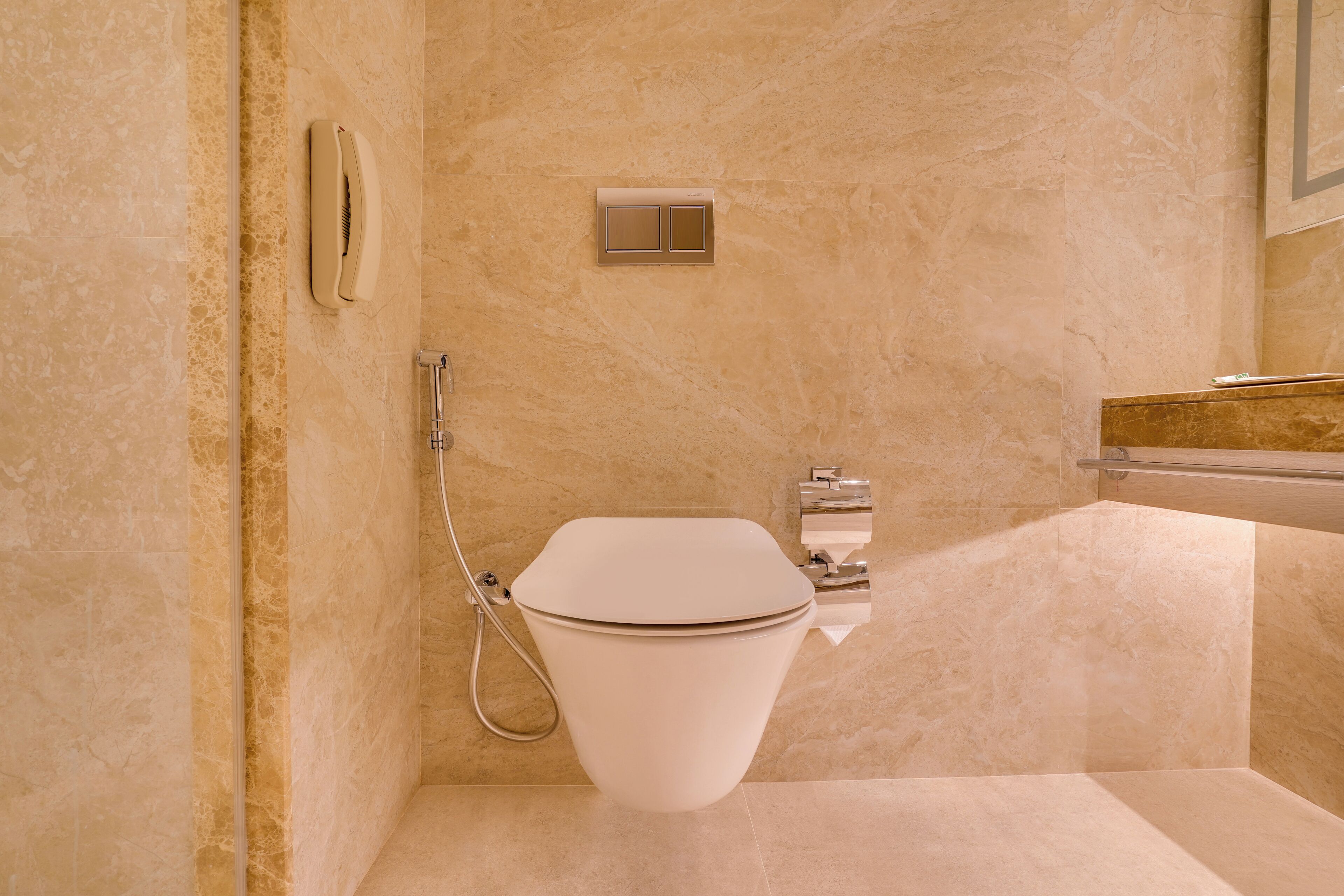 A modern bathroom with a toilet, a hand dryer, and a towel rack.