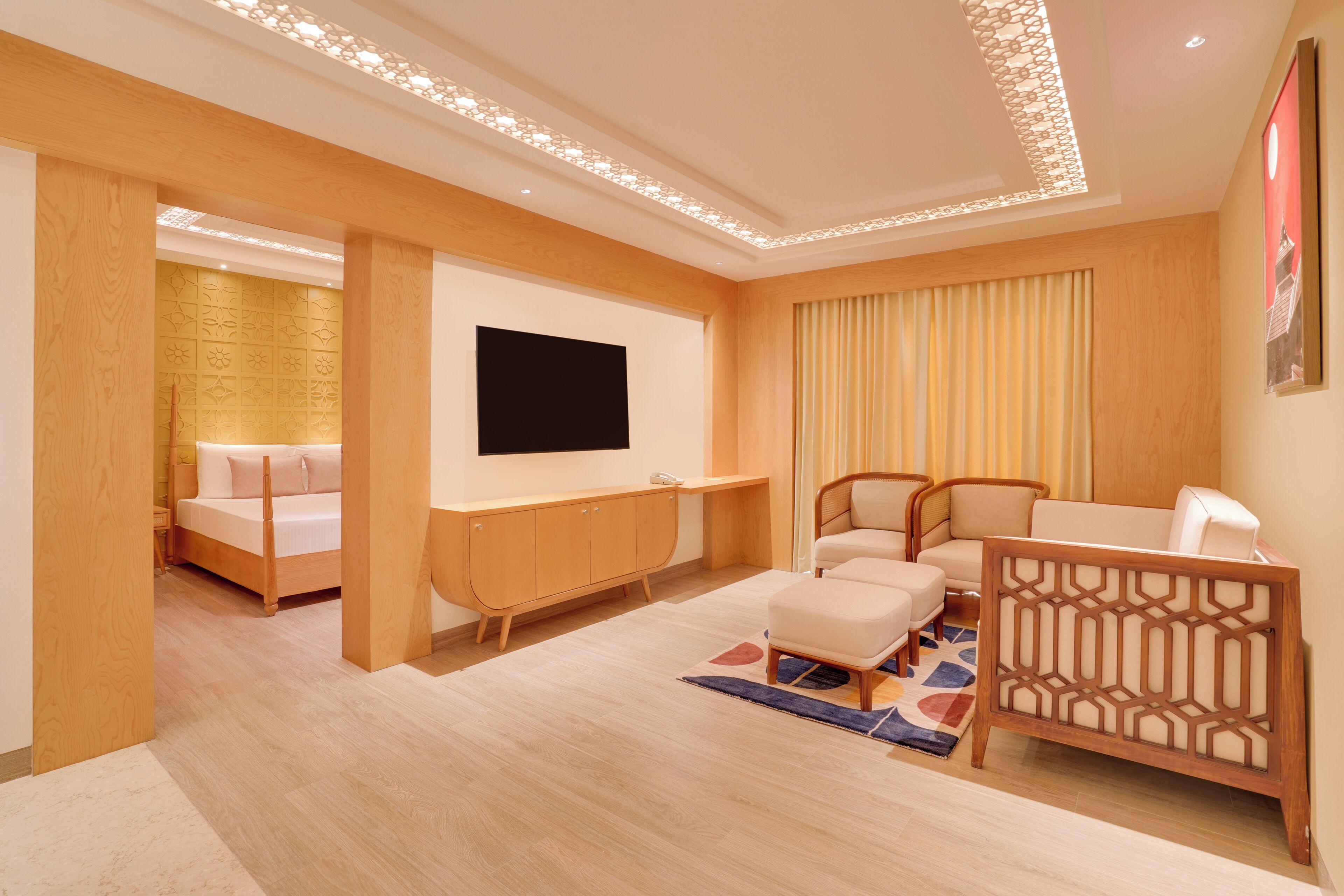 A modern hotel room with a bed, a desk, a TV, and a seating area.
