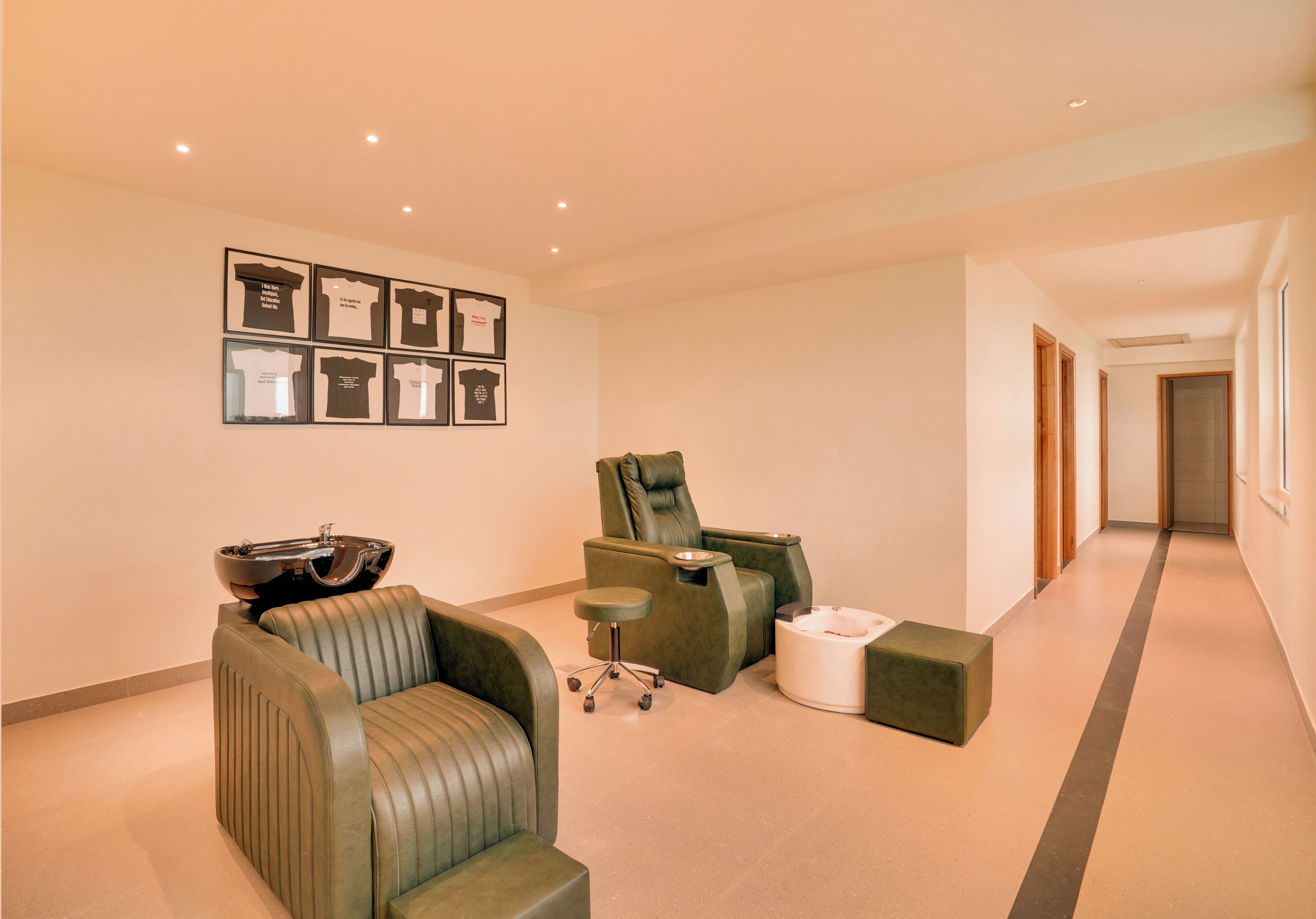 A modern lounge area with leather sofas, a massage chair, a small table, and framed t-shirts on the wall.