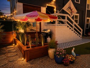 A patio with a barbecue grill, a covered seating area, and a staircase leading to a second floor.