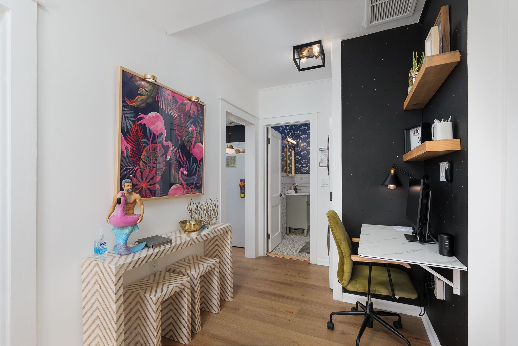 Une chambre moderne avec un bureau en bois, une chaise, un grand tableau et un mur noir agrémenté d’étagères.