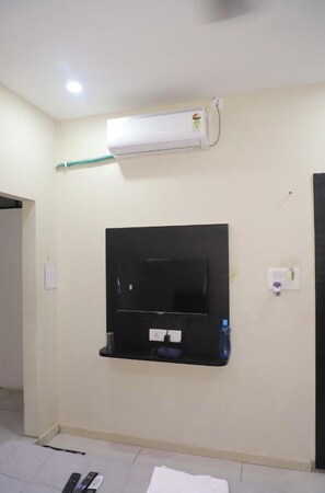 A room with a mounted flat-screen TV, an air conditioning unit, and a power outlet on the wall. - Satkar home stay ujjain (Ujjain)