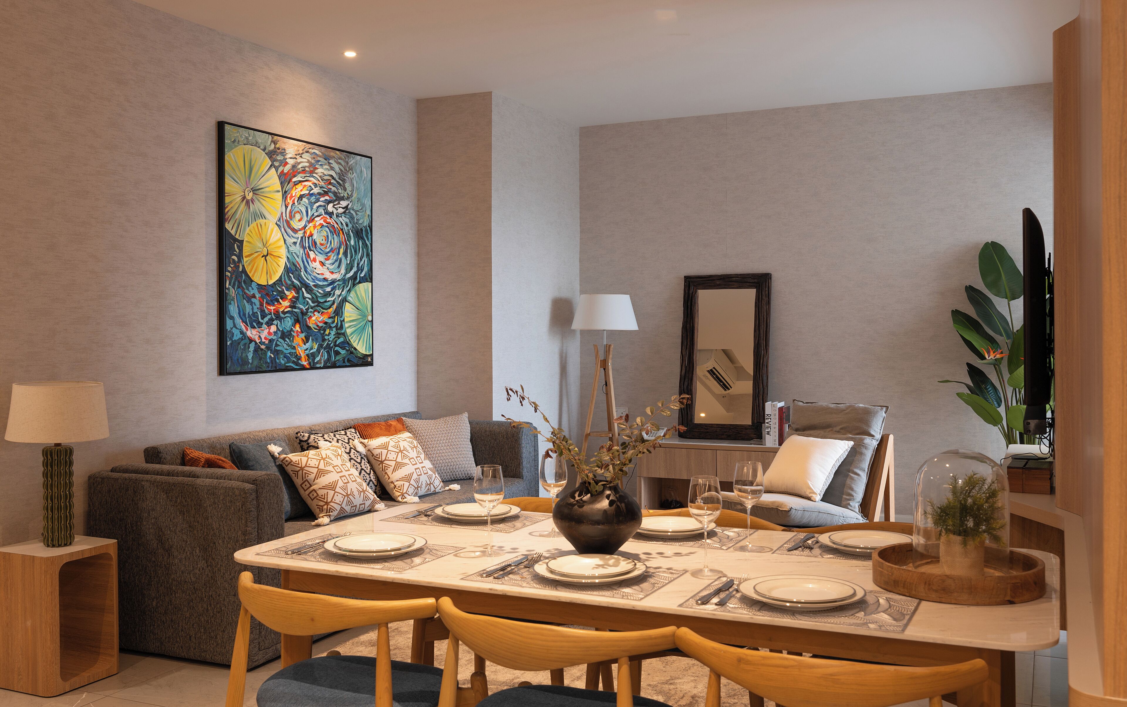 A dining area with a table set for four, a sofa, a lamp, and a painting on the wall.