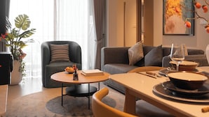 Una sala de estar moderna con un sofá, una mesa de comedor y un ventanal con cortinas.