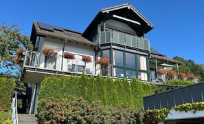 Un edificio di due piani con balconi, ampie finestre e pannelli solari.