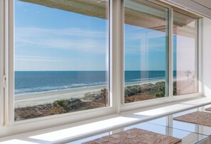 A room with a large window overlooking a beach.
