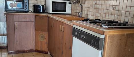 A kitchen with wooden cabinets, a microwave, a toaster, and a dishwasher.