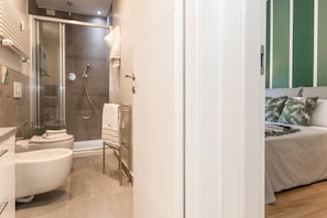 A modern bathroom with a glass-enclosed shower, a freestanding bathtub, and a toilet.