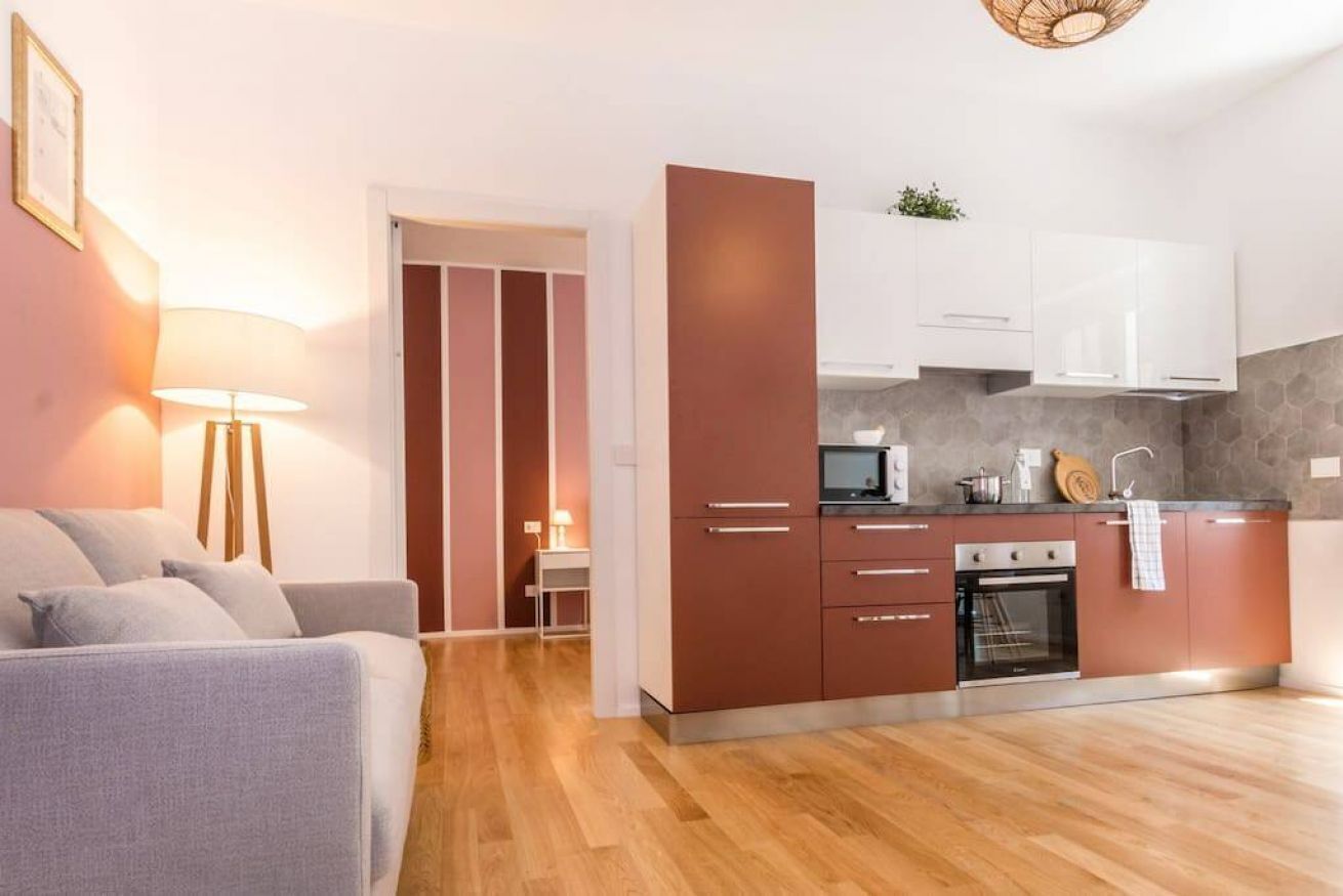 Een moderne keuken met houten vloeren, witte kasten en een inbouwoven.