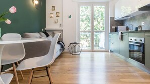 A modern kitchen with a dining area, wooden flooring, and a view through a glass door. - 2 Combined Flats Near CityLife District (Milan)