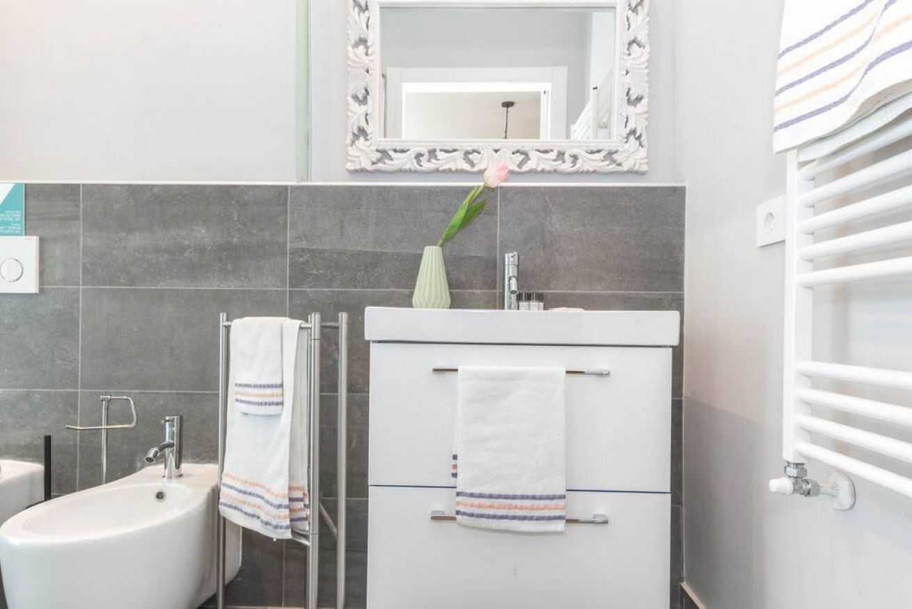A bathroom with a white sink, a mirror with a decorative frame, a towel rack, and a towel hanging on the wall.