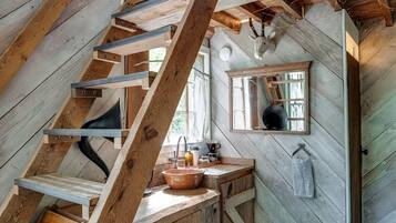 Ein rustikales Blockhaus-Interieur mit einer Holztreppe, einer Küchenzeile inklusive Spüle und einem Fenster mit Blick.