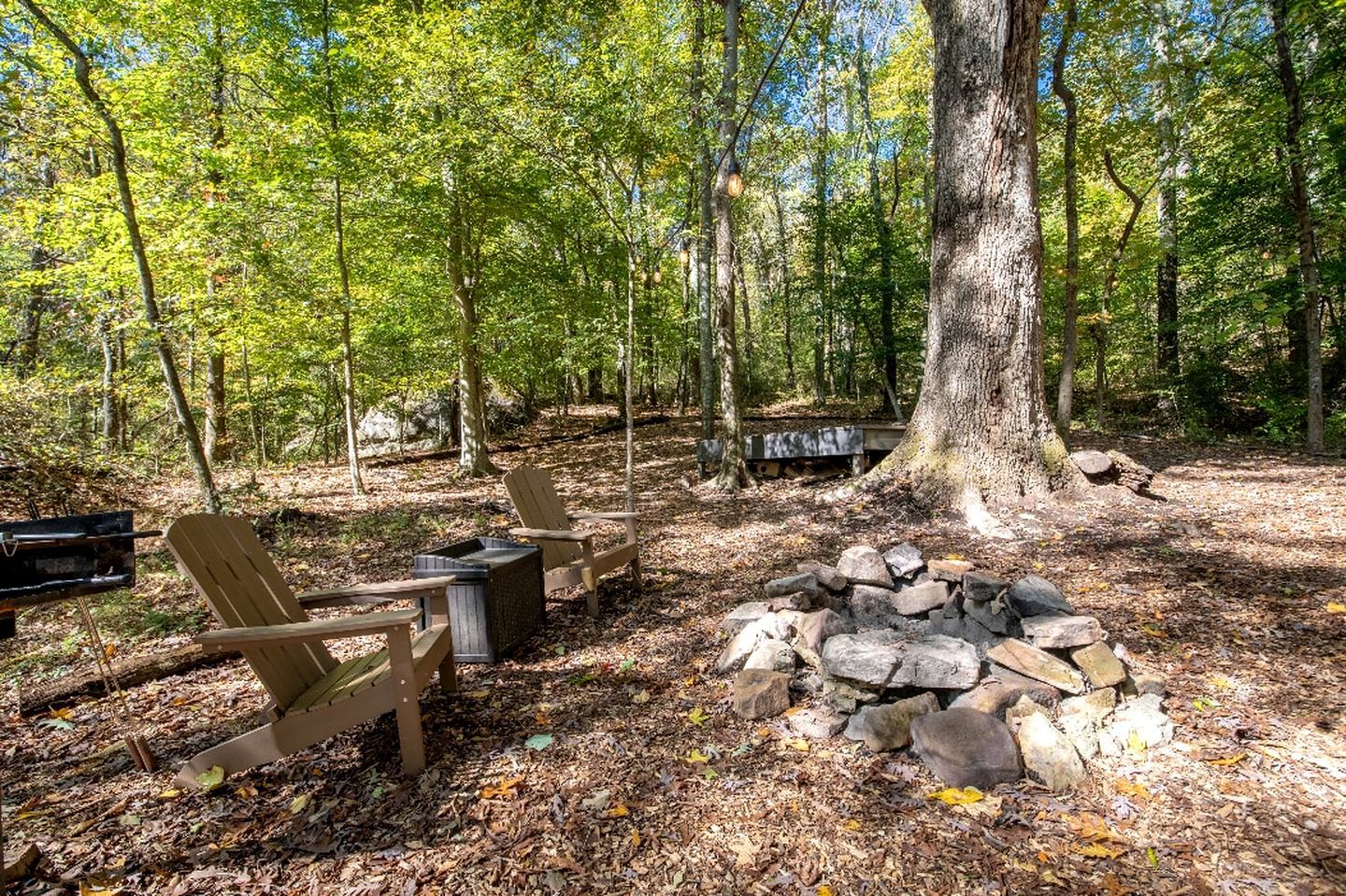 Un terrain de camping équipé de chaises en bois, d’un foyer et d’une table de pique-nique.