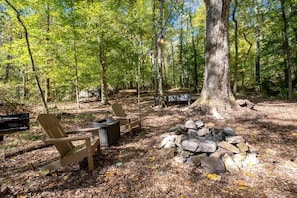 A campsite with wooden chairs, a fire pit, and a large tree. - Secluded Tree House in the Forest near the Appalachian Mountains, Georgia (Flintstone)