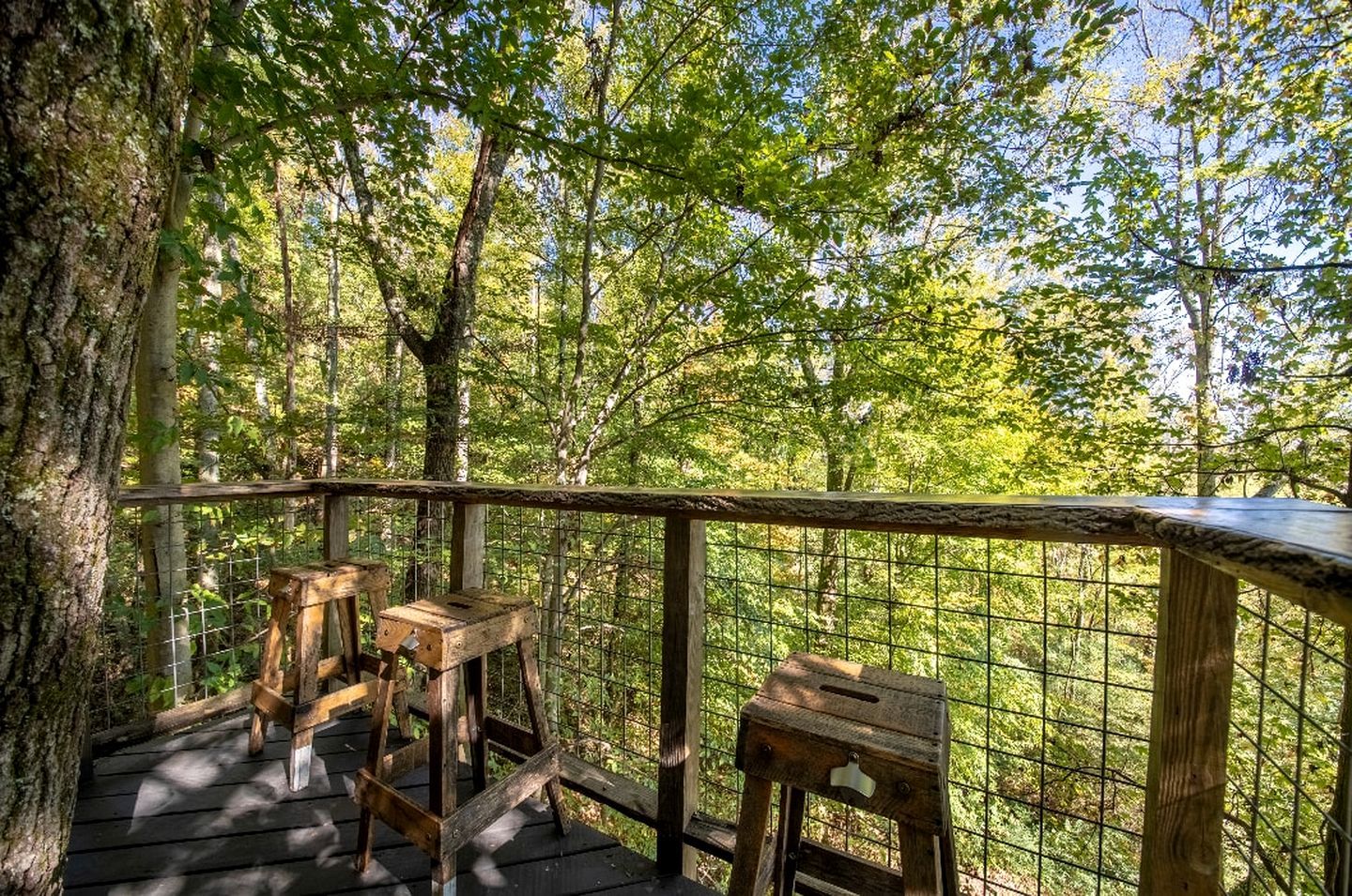 A wooden deck with a railing overlooking a forested area.