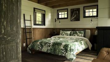 A bedroom with a bed, wooden walls, a ladder, and a door.