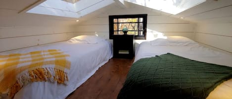 Una habitación con dos camas, un tragaluz y una ventana.