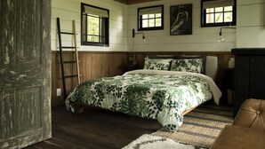 A bedroom with a bed, wooden walls, a ladder, and a door. - Romantic Tree House near Chattanooga in the North Georgia Woodlands (Flintstone)