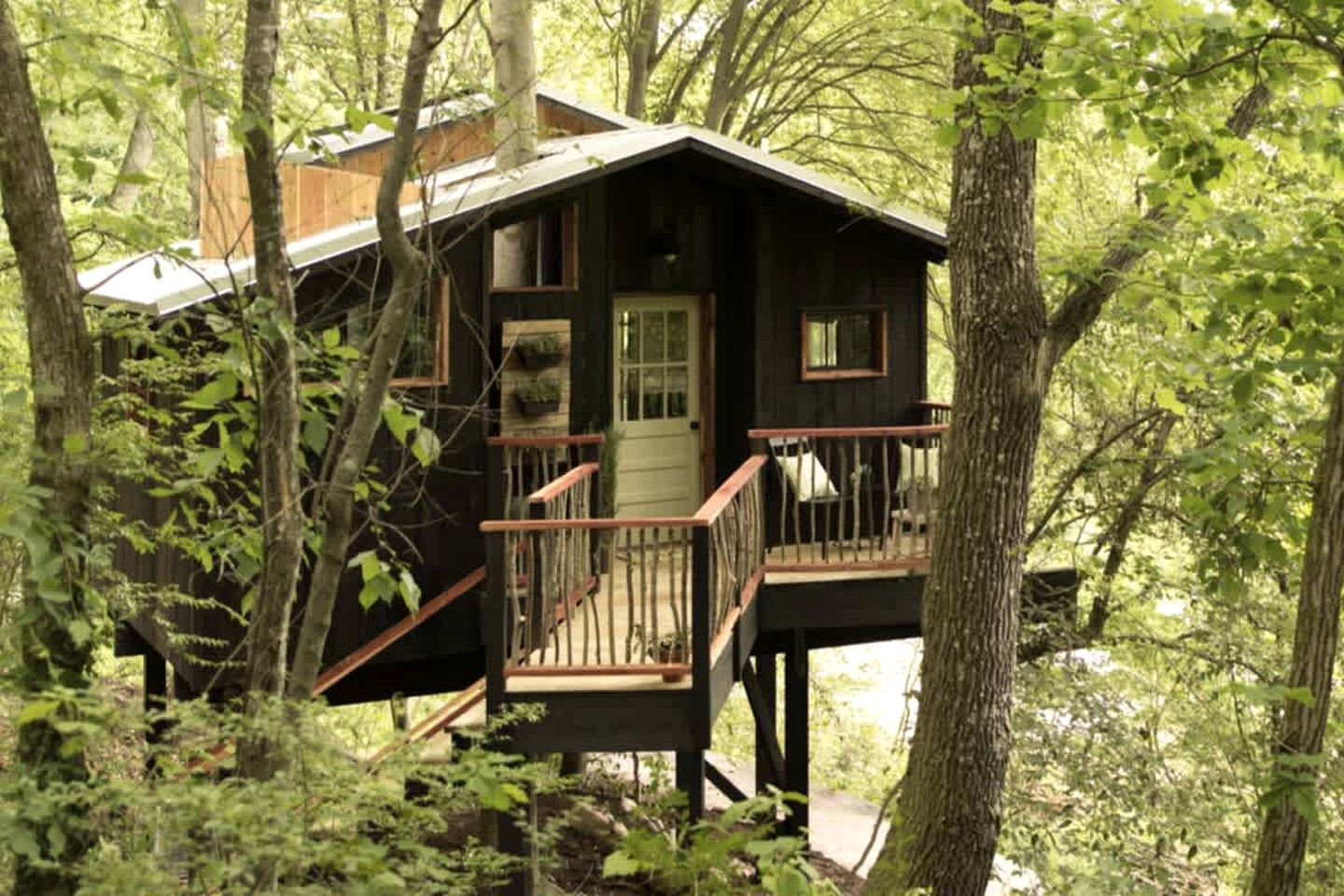 Une cabane dotée d’une terrasse en bois, d’une porte d’entrée et d’un petit porche.