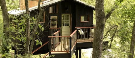 A cabin with a wooden deck, a front door, and a small porch.