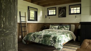 A bedroom with a bed, wooden walls, a ladder, a window, and a door.