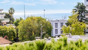 A coastal residential area with modern buildings, lush greenery, and a view of the sea.