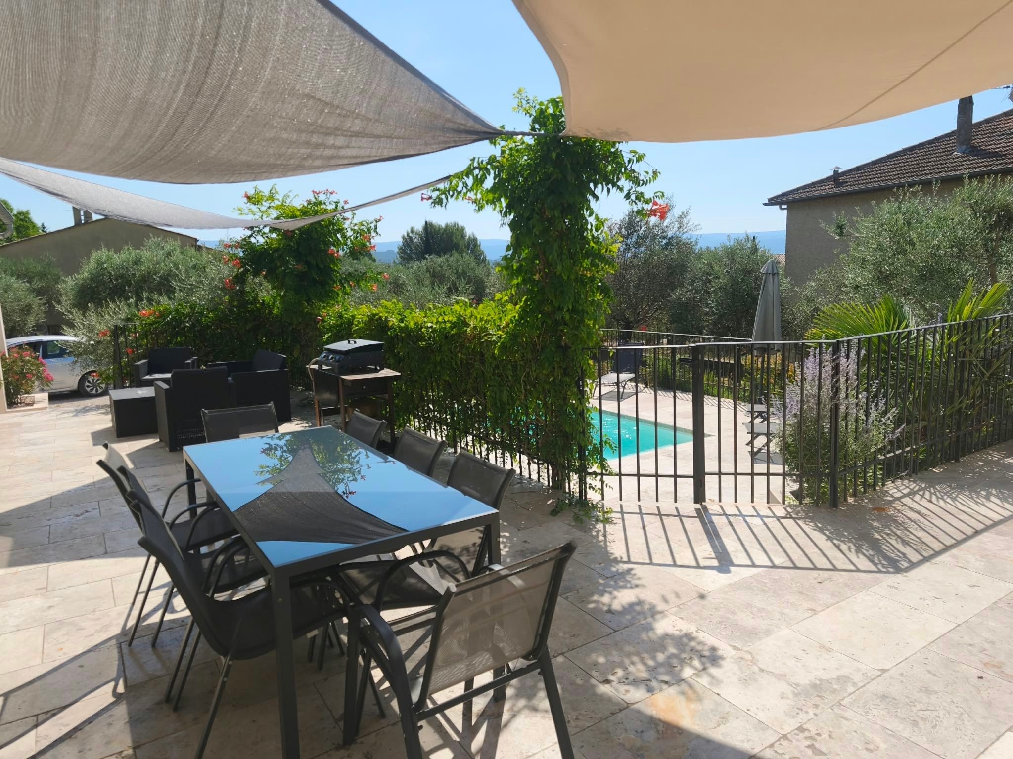 An outdoor patio area with a table and chairs, a barbecue grill, and a swimming pool.