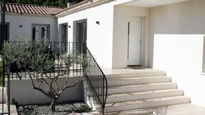 Un bâtiment moderne à l’extérieur blanc, doté d’un toit recouvert de tuiles et d’un escalier menant à une porte.