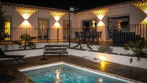 Un espace aménagé au bord de la piscine, comprenant une piscine, des marches menant à un patio couvert et une clôture.