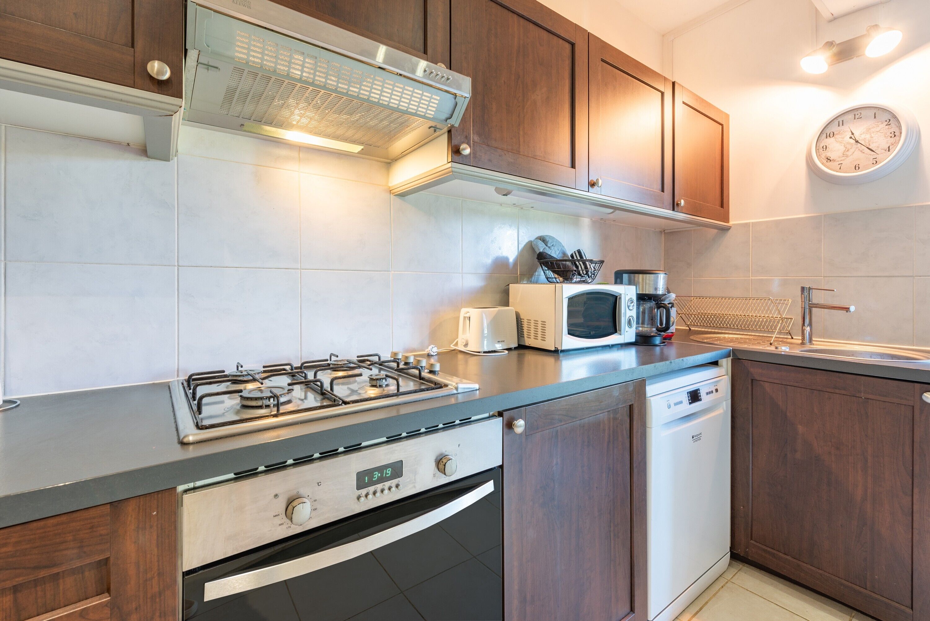 A modern kitchen with a gas stove, microwave, dishwasher, and wooden cabinets.