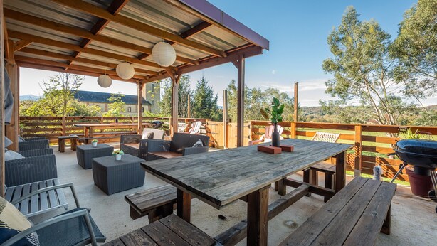 An outdoor patio with wooden tables and chairs, a covered seating area, and a barbecue grill. - Holiday Home “Galets” with Mountain View, Wi-Fi, and Air Conditioning (Peyraube)