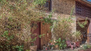 A rustic stone building with a wooden door, potted plants, and outdoor seating. - Holiday Home “Galets” with Mountain View, Wi-Fi, and Air Conditioning (Peyraube)