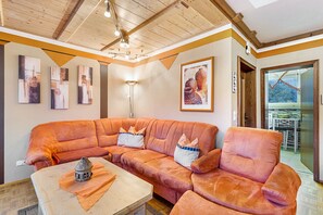 Una sala de estar con un amplio sofá modular naranja, una mesa de centro de madera y una lámpara de pie.