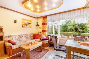 Ein gemütliches Wohnzimmer mit einer Couch, einem Esstisch und Blick auf einen Garten.