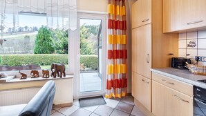 Eine Küche mit Holzausstattung, einem Toaster und Blick auf eine grüne Landschaft durch eine Glastür.
