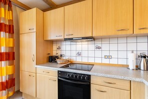 Eine Küche mit Holzausstattung, einem schwarzen Herd und einer gefliesten Spritzschutzwand.