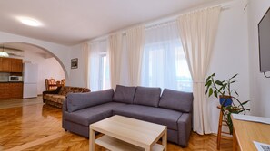 Una sala de estar con sofá, mesa de centro, televisor y planta.