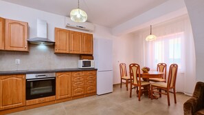 Una cocina compacta con armarios de madera, un microondas, una estufa y un comedor con mesa y sillas.