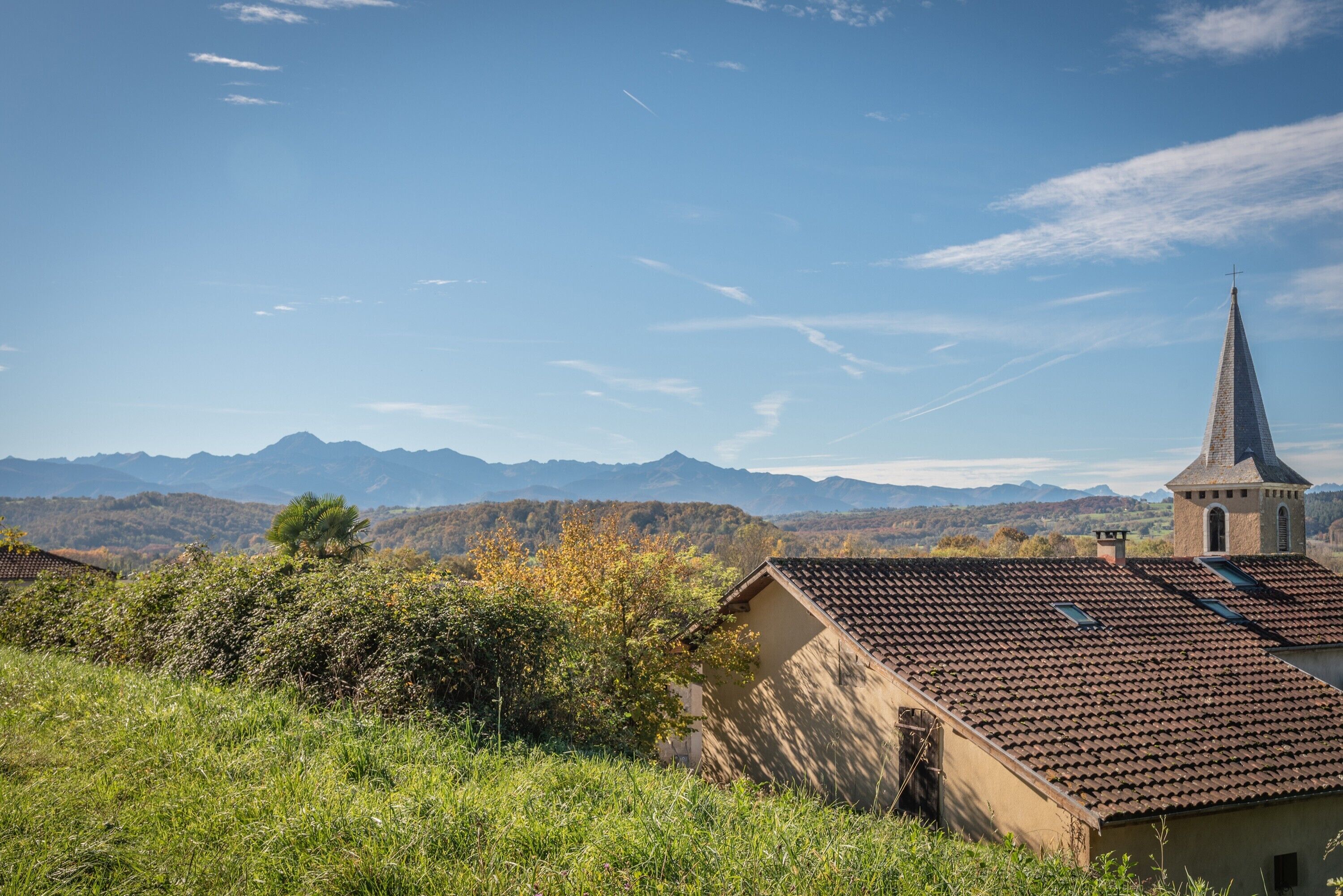 A rural landscape with a church, mountains, and a clear sky.