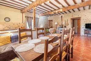 A rustic dining area with wooden furniture, a stone wall, and a tiled floor.
