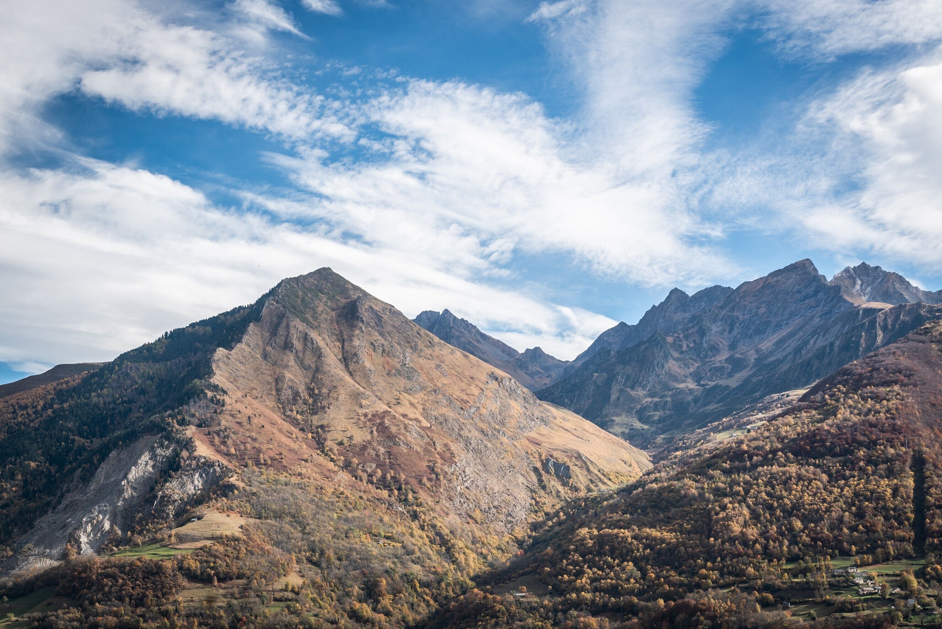 A mountainous landscape with a valley and a small settlement.