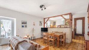 A cozy room with a bed, a dining table, and a TV. - Gary Loup Holiday Home: Mountain View, Private Terrace, Wi-Fi (sazos)