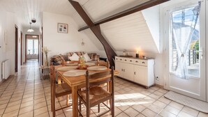 A dining area with a wooden table and chairs, a sofa, and a cabinet.